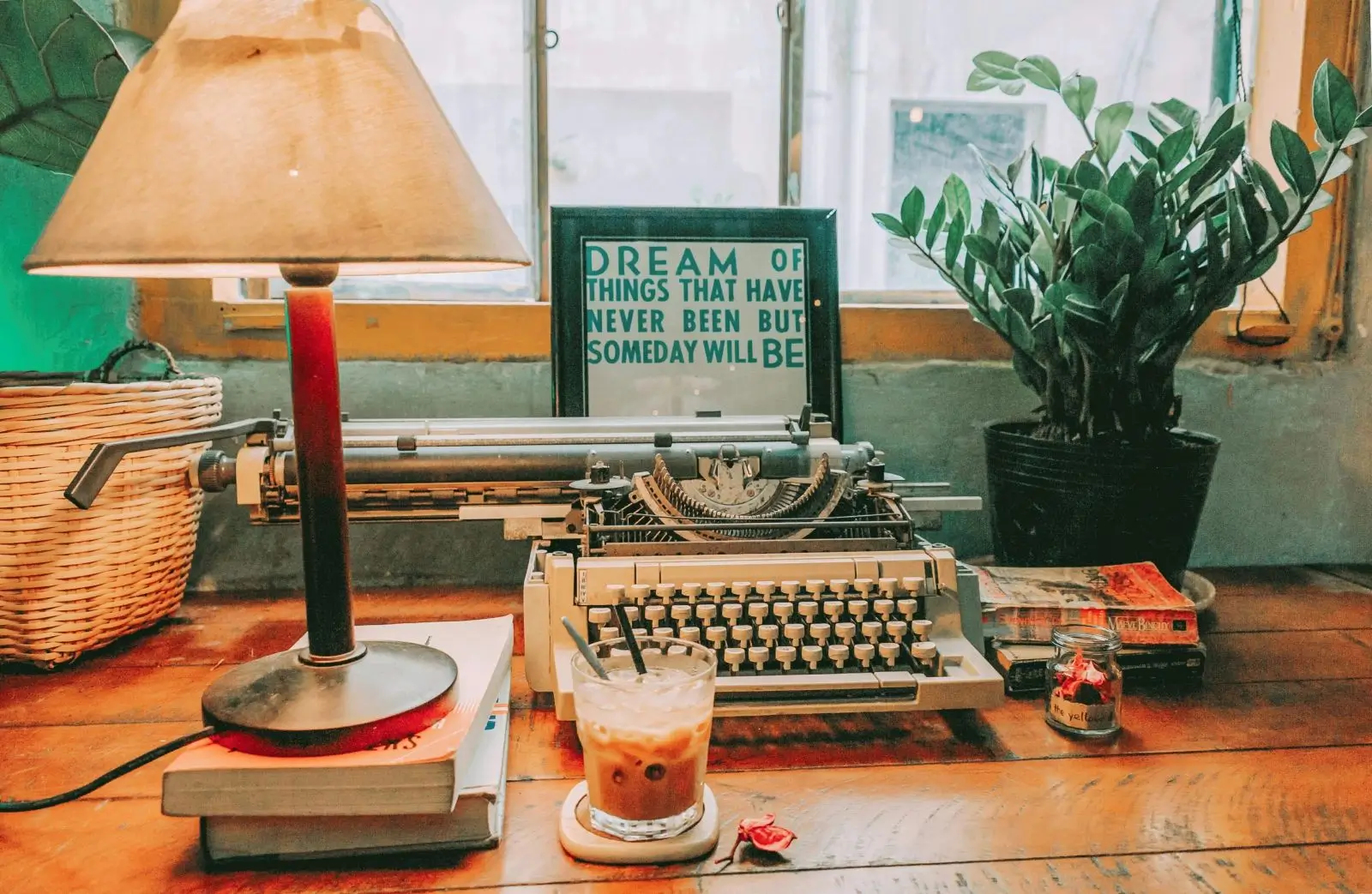 A desk with a typewriter and a glass of coffee.