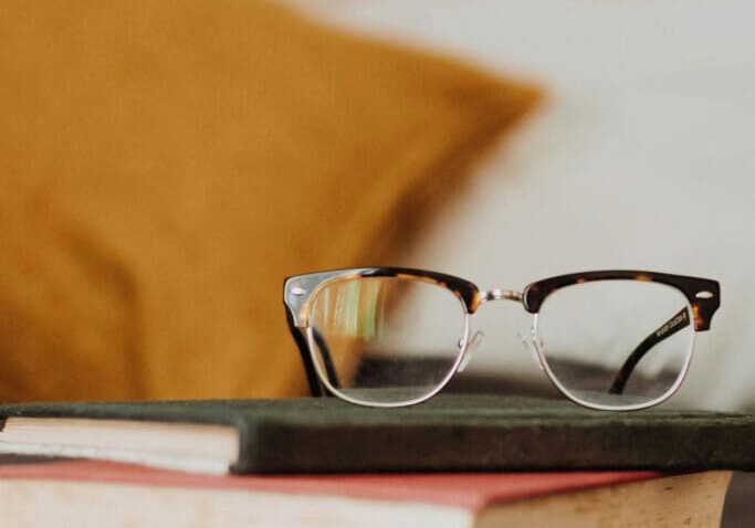 A pair of glasses sitting on top of some books.